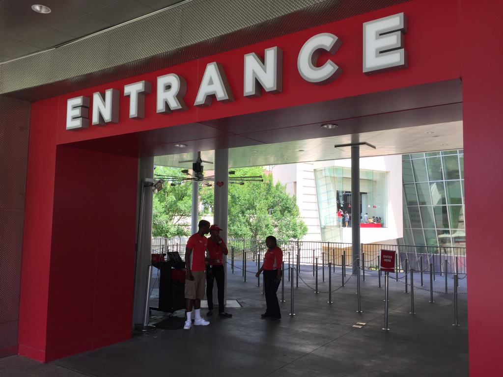 Vstup do World of Coca‑Cola, nápis ENTRANCE, zaměstnanci a prázdné turnikety