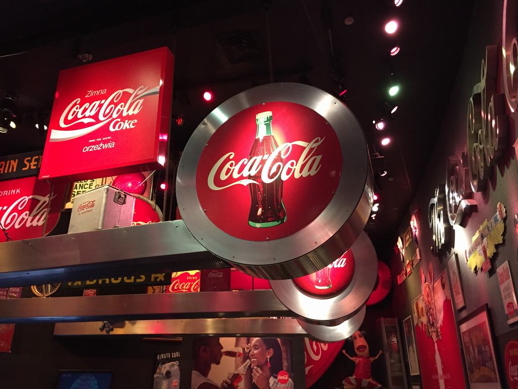 Expozice s kruhovými logy Coca-Cola a cedulí Zimna Coca-Cola Coke orzeźwia.