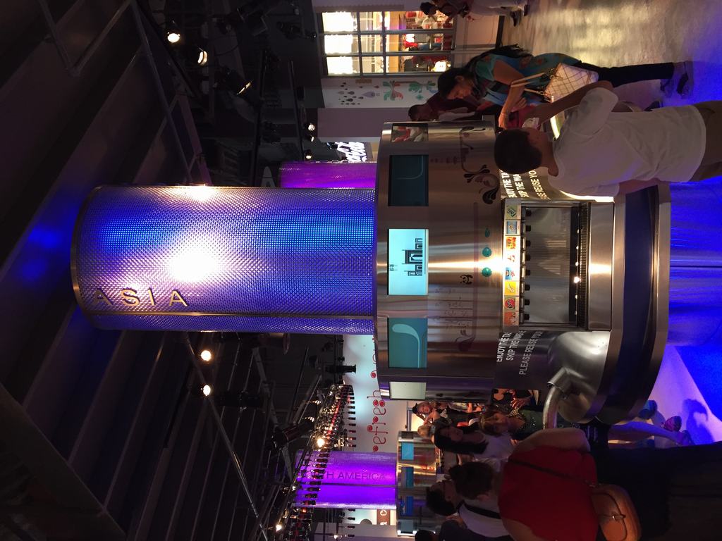 Ochutnávkový automat ve World of Coca‑Cola, věž s nápisem ASIA, návštěvníci kolem