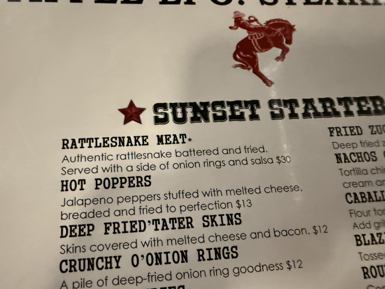 Menu with rattlesnake meat, Sunset Starter, and cowboy horse logo at restaurant.