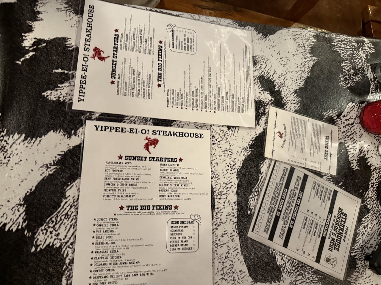 Menu jídel Yippee-Ei-O! Steakhouse na kravském vzoru stolu, včetně rašelinových jídel a steaků.