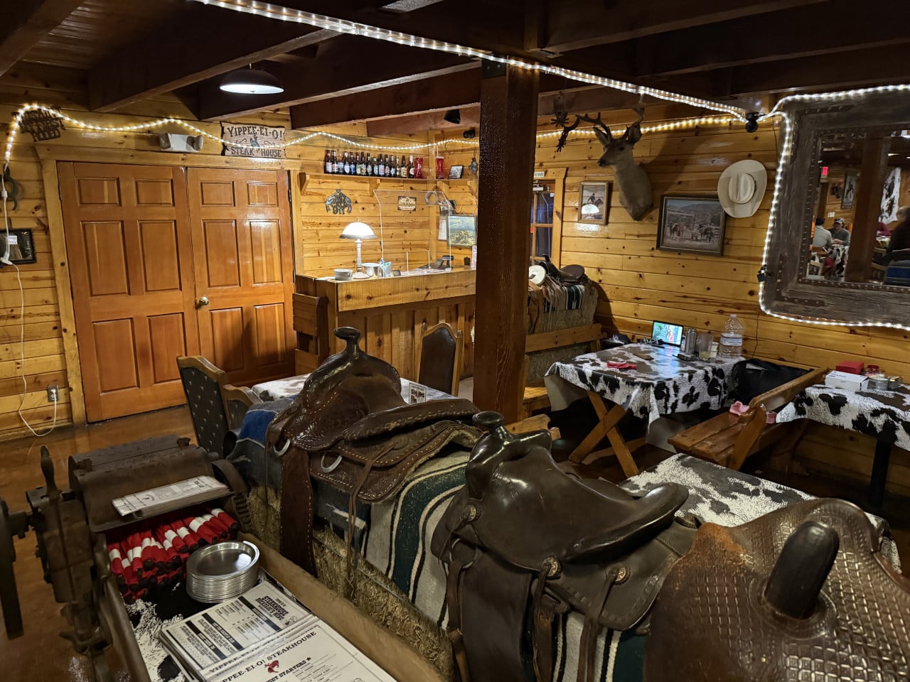 Interiér westernového steakhousu s koženými sedly, dřevěnými stěnami a stříbrným osvětlením.